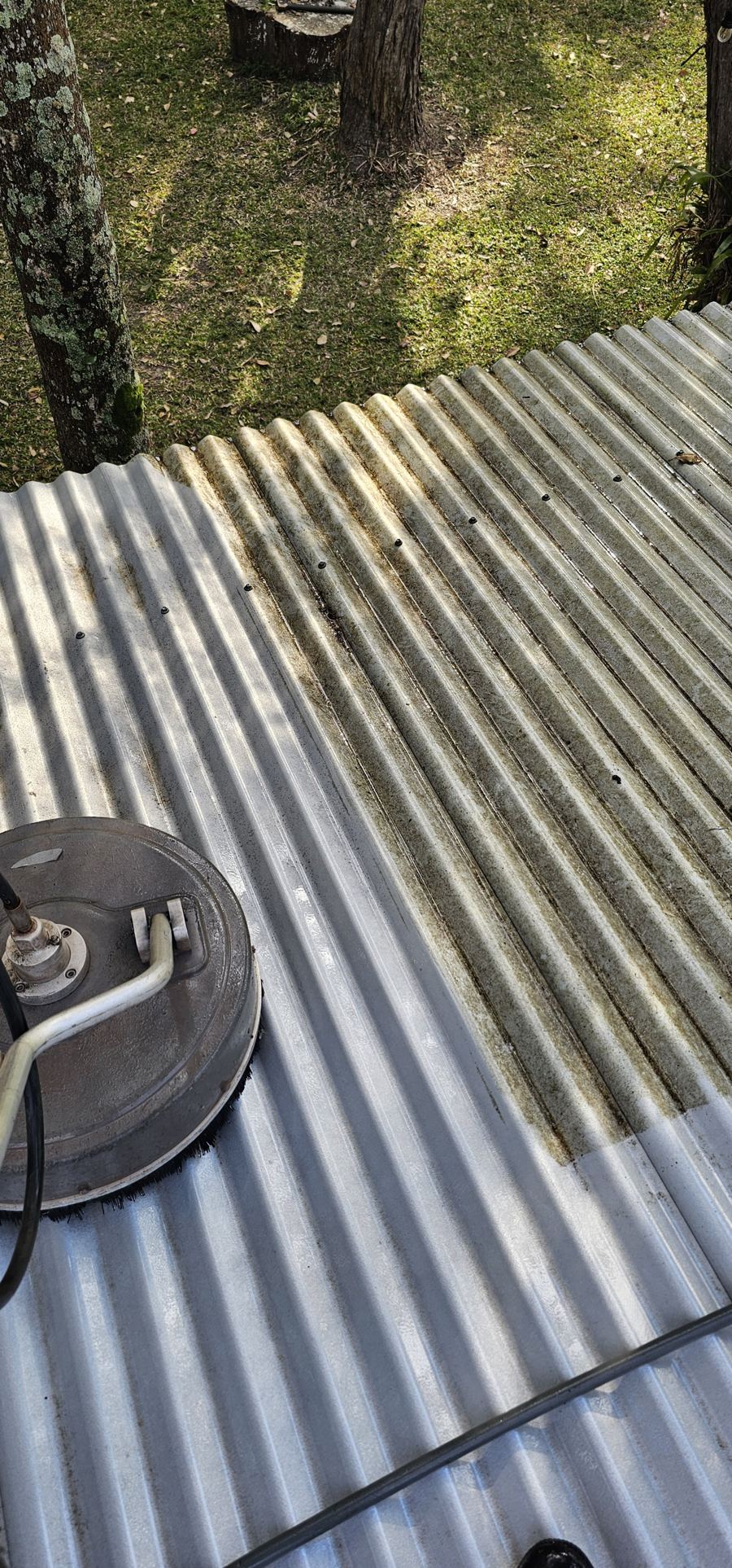 Rotary brush cleaning a corrugated metal roof