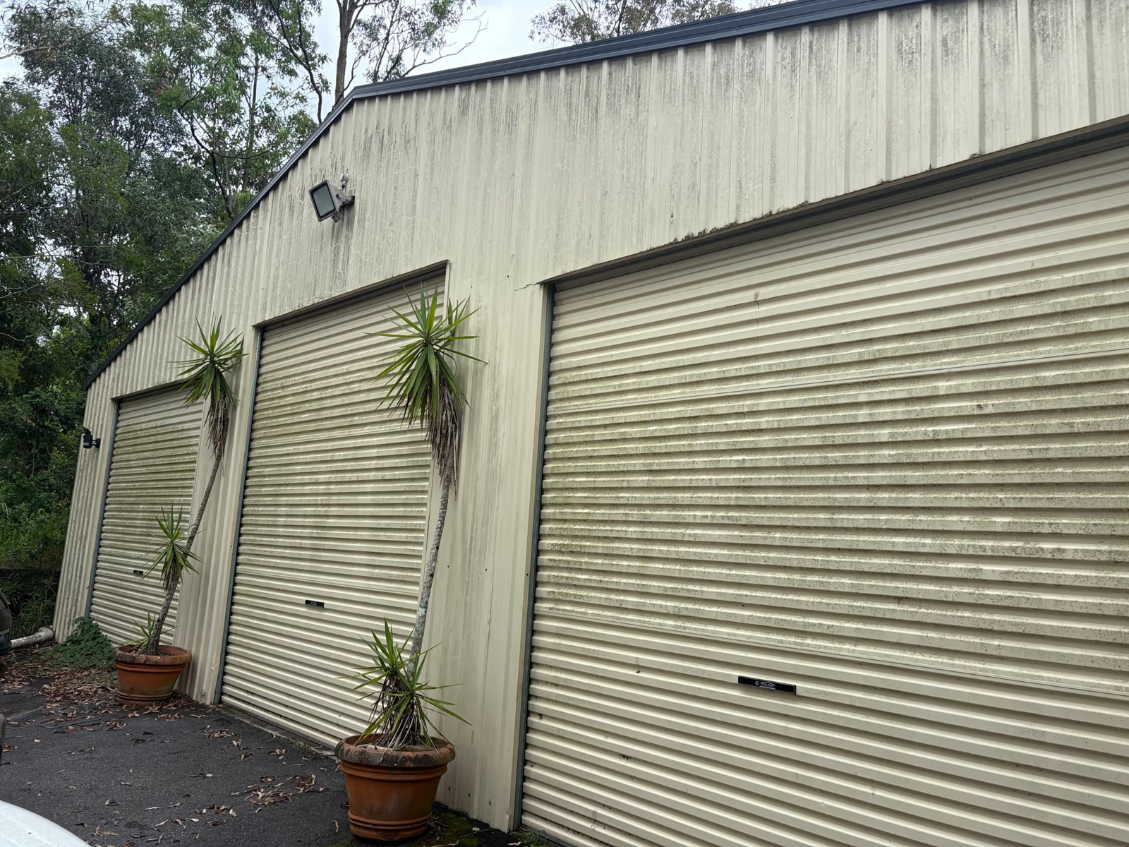 Same commercial shed before cleaning, walls and doors covered in grime and weather staining