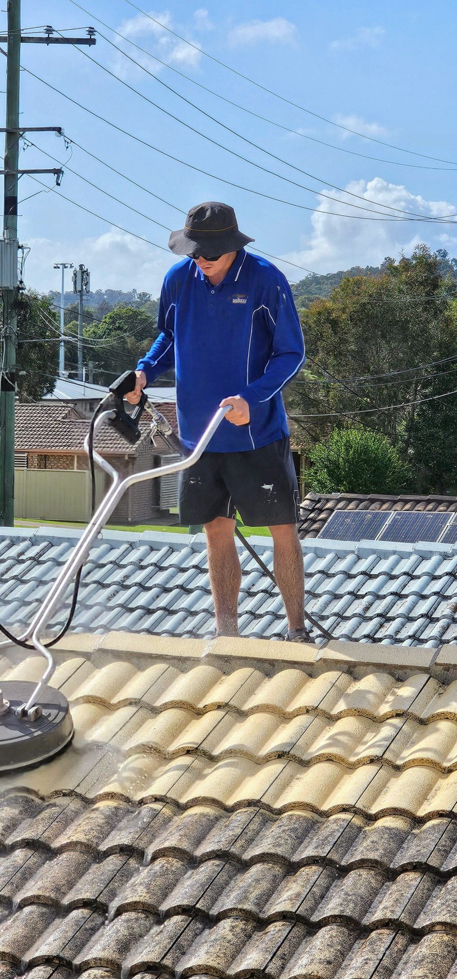 Technician soft washing a tiled roof
