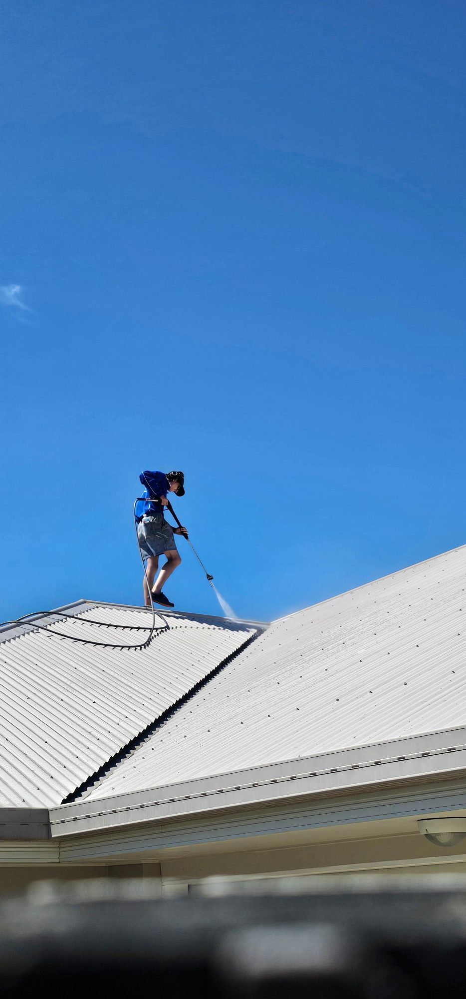 Technician soft washing a colorbond roof