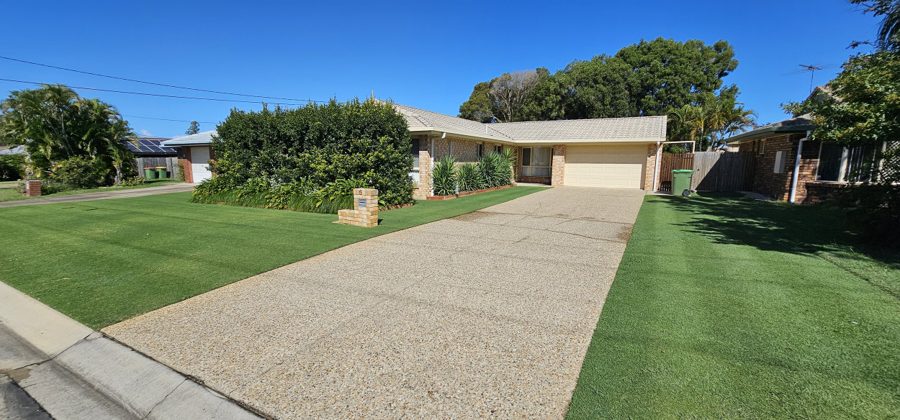 Clean concrete driveway in front of a brick home
